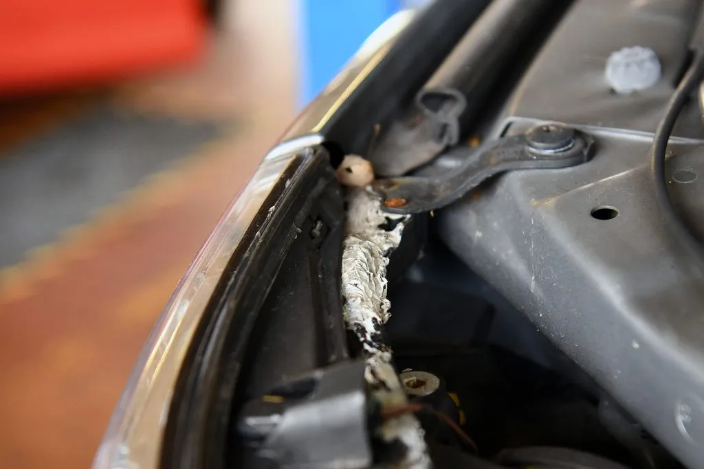 Uszkodzone mocowanie reflektora BMW E60 ze śladami wcześniejszej naprawy