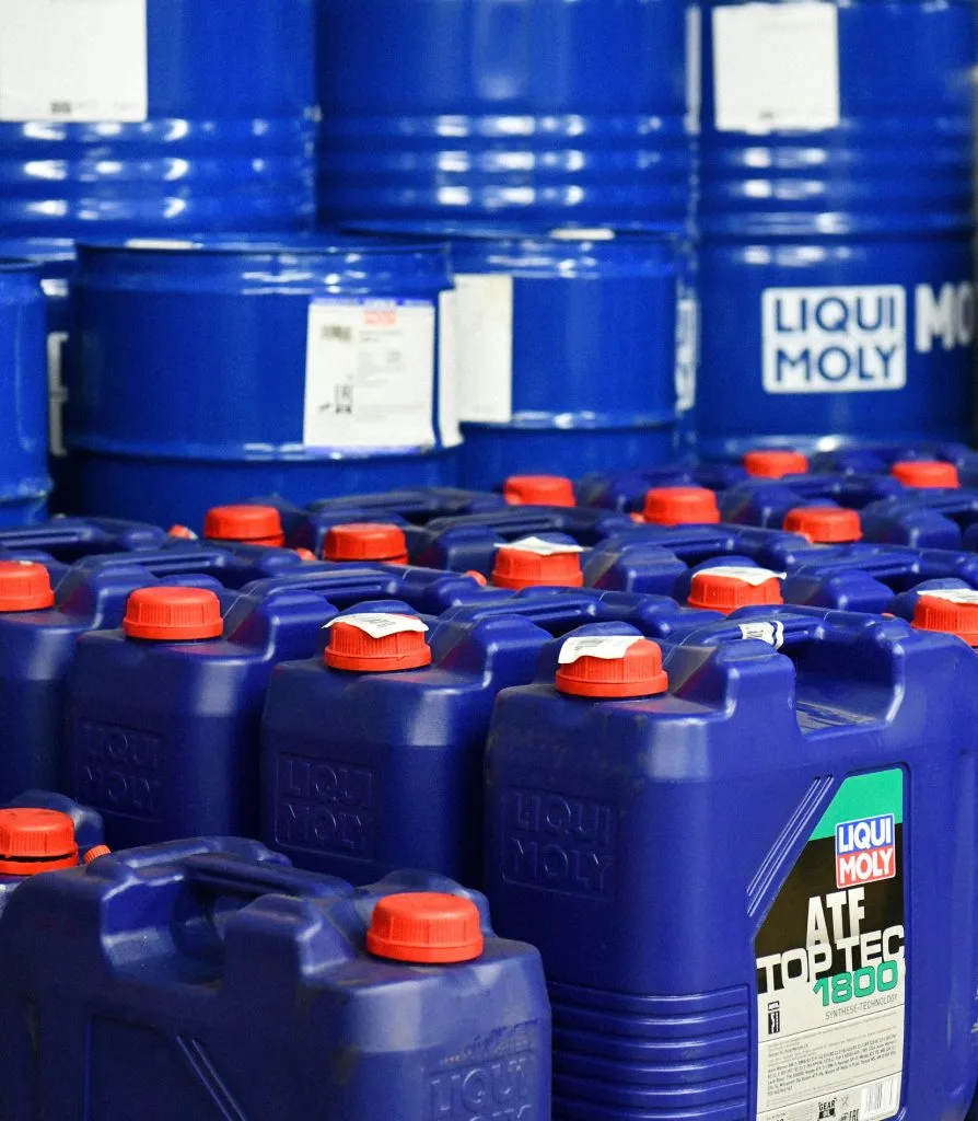Kanistry produktów Liqui Moly ustawione przed beczkami oleju