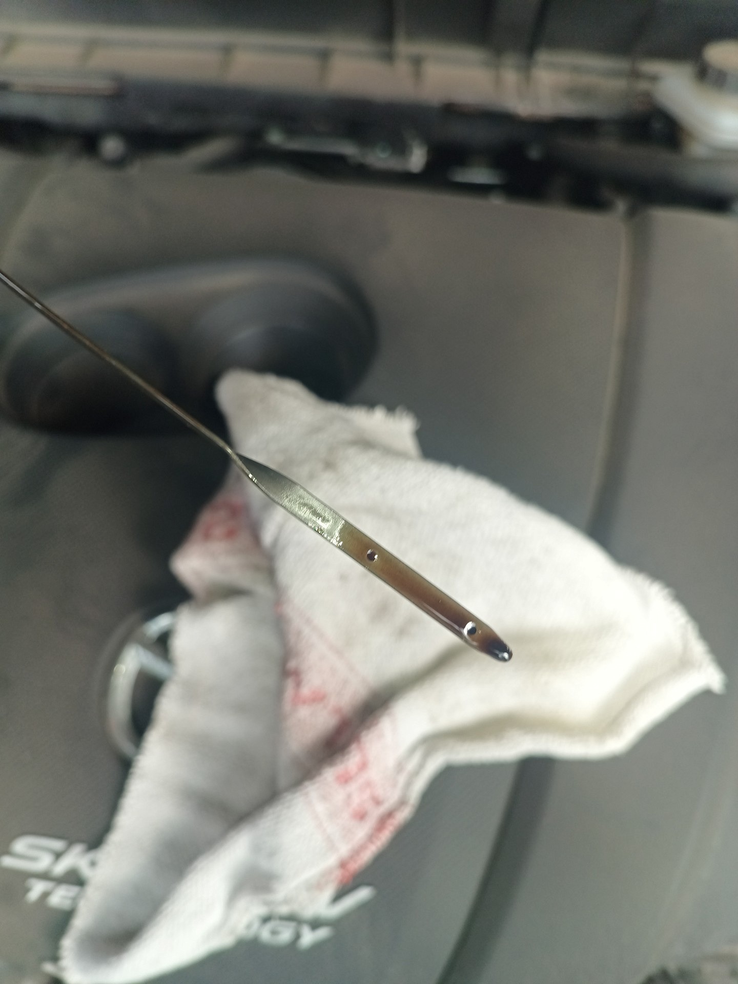 Końcówka bagnetu oleju nad szmatką na pokrywie silnika Mazdy CX-3