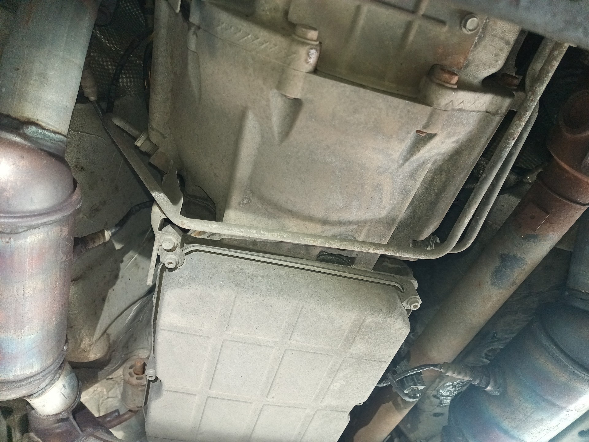 Obudowa skrzyni biegów Dodge’a Nitro Van widziana od spodu, między rurami wydechu